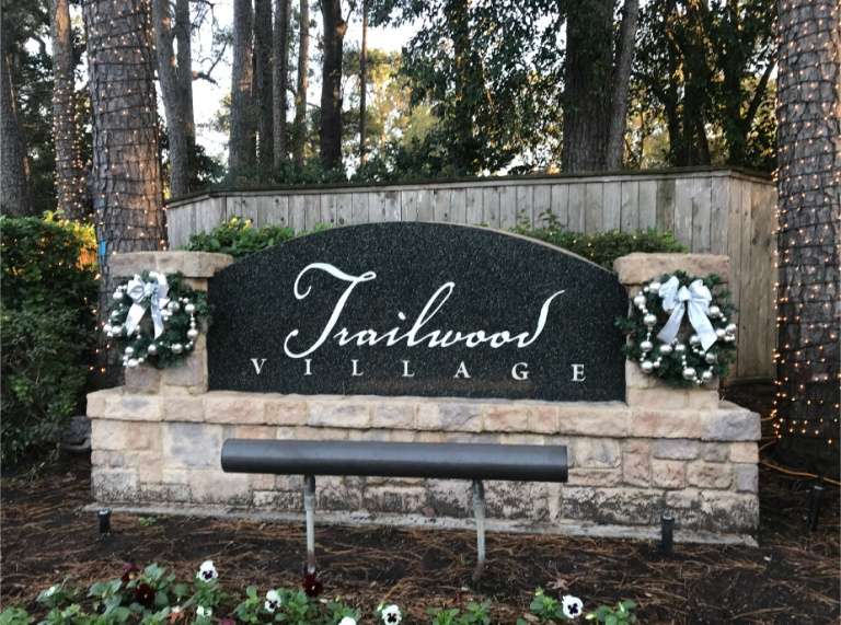 Trailwood Village entrance sign in Kingwood decorated with Christmas garland and red bows